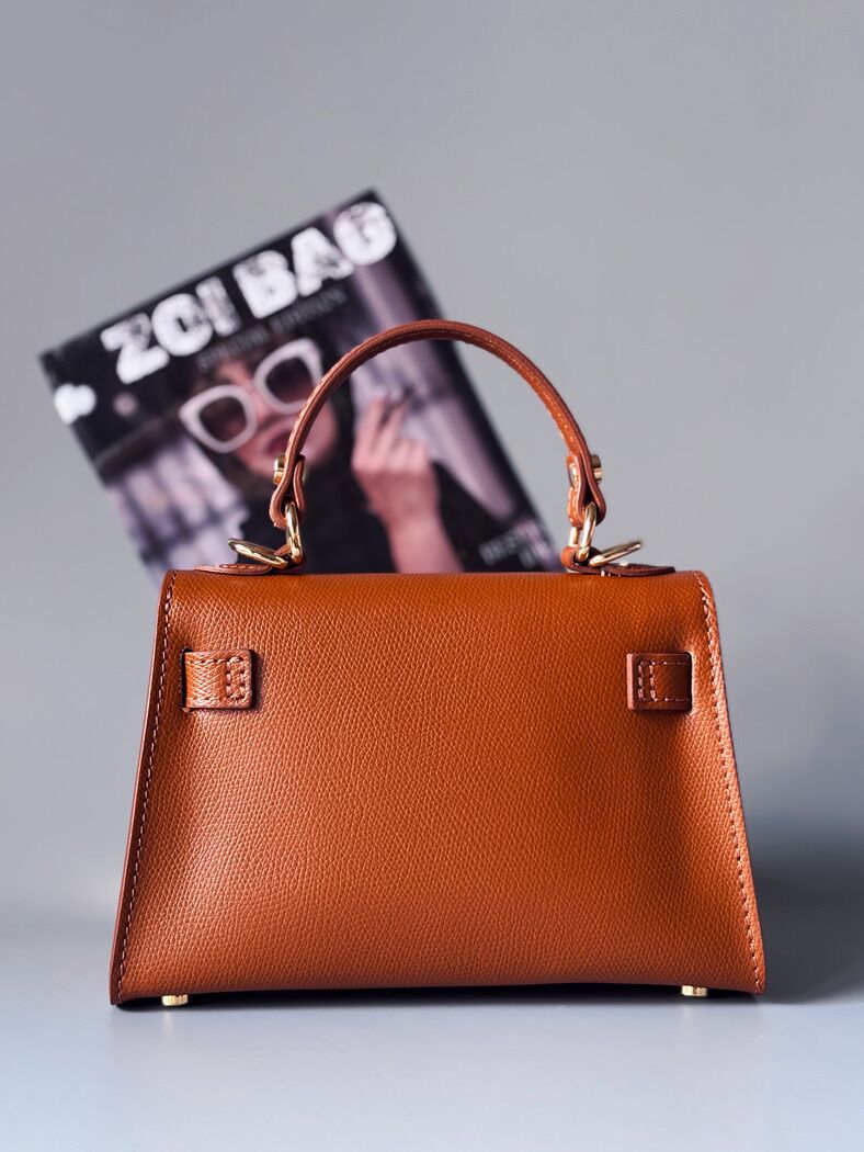 Designová luxusní hnědá kabelka s ručně psaným nápisem, elegantním otočným zámkem a odnímatelným crossbody popruhem. Zezadu.