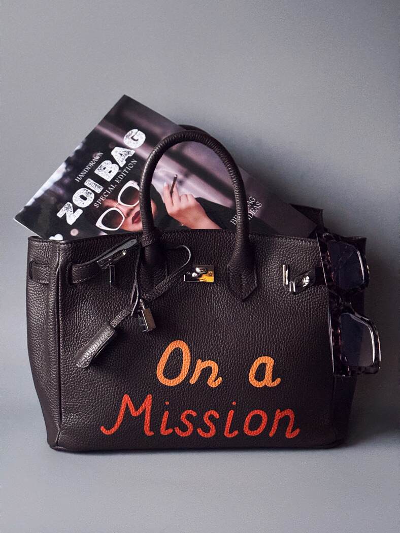 Kožená kabelka Zoi Bag v tmavě hnědé výrazné barvě s oranžovým nápisem "On a Mission"