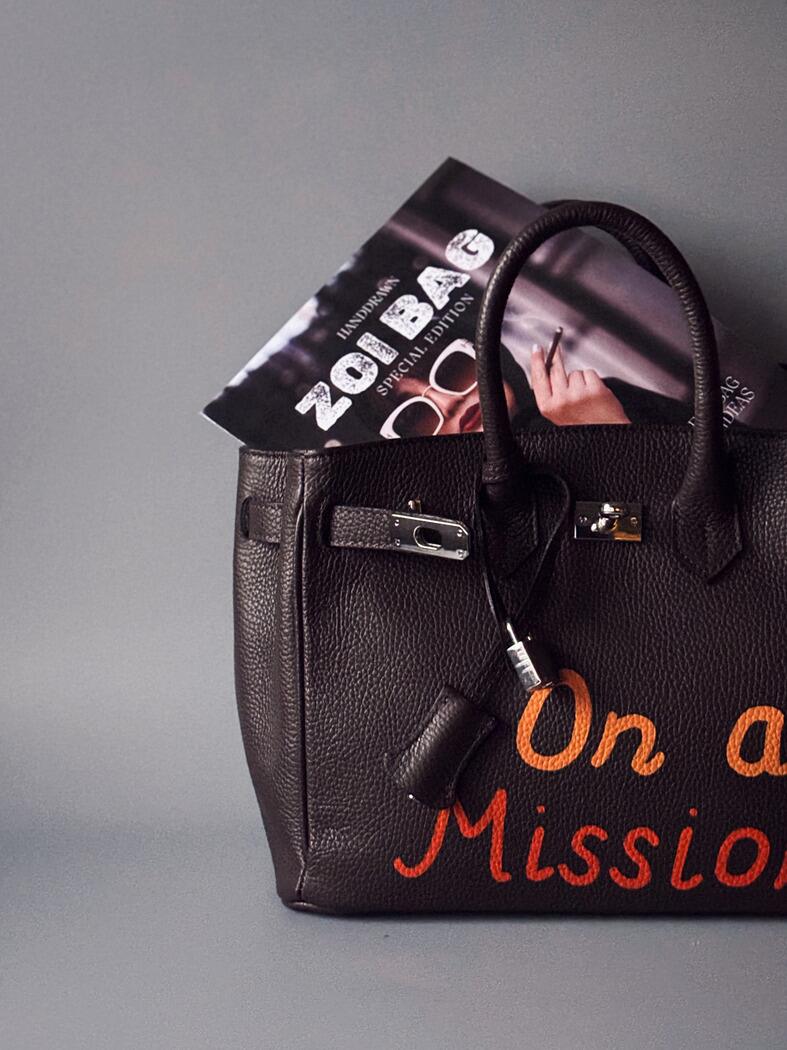 Art tmavě hnědá kožená kabelka Zoi Bag s nápisem "On a Mission" detail