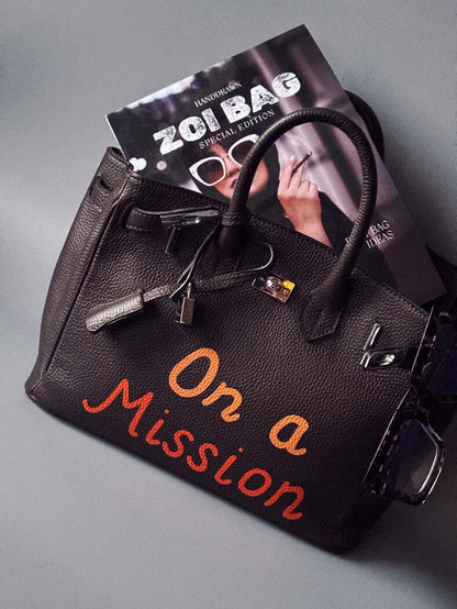 Tmavě hnědá kožená kabelka Zoi Bag s nápisem "On a Mission" z kolekce "Love for Life"