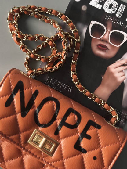 Hnědá kožená crossbody kabelka Zoi Bag s ručně psaným černým nápisem "Nope" detai