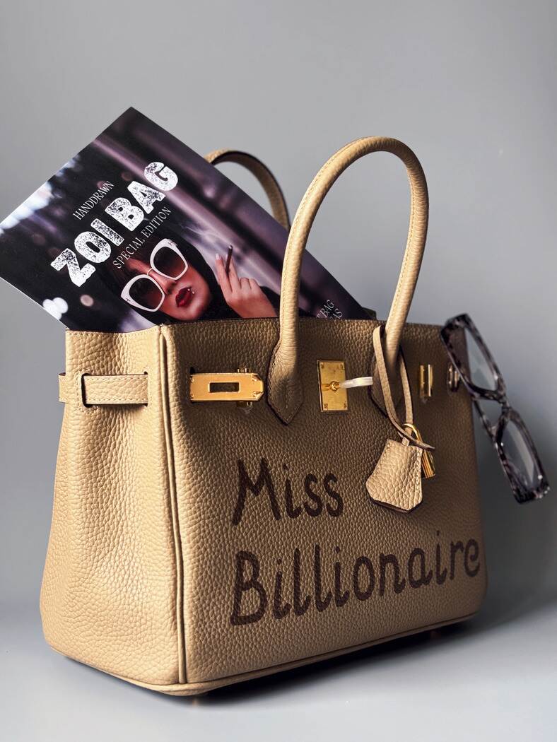 Kožená art kabelka Zoi Bag v béžové barvě s nápisem "Miss Billionaire" z boku