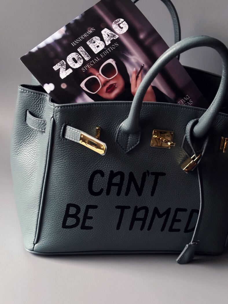 Kožená šedomodrá kabelka Zoi Bag s ručně psaným nápisem "Can't be tamed"