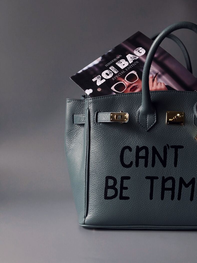 Kožená prostorná šedomodrá kabelka Zoi Bag s ručně psaným nápisem "Can't be tamed"