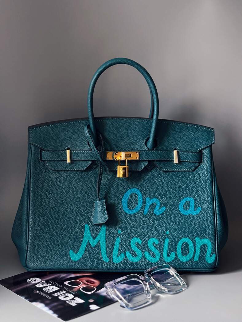 Stylová modrá kožená kabelka Zoi Bag s nápisem "On a Mission"