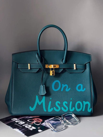 Stylová modrá kožená kabelka Zoi Bag s nápisem "On a Mission"