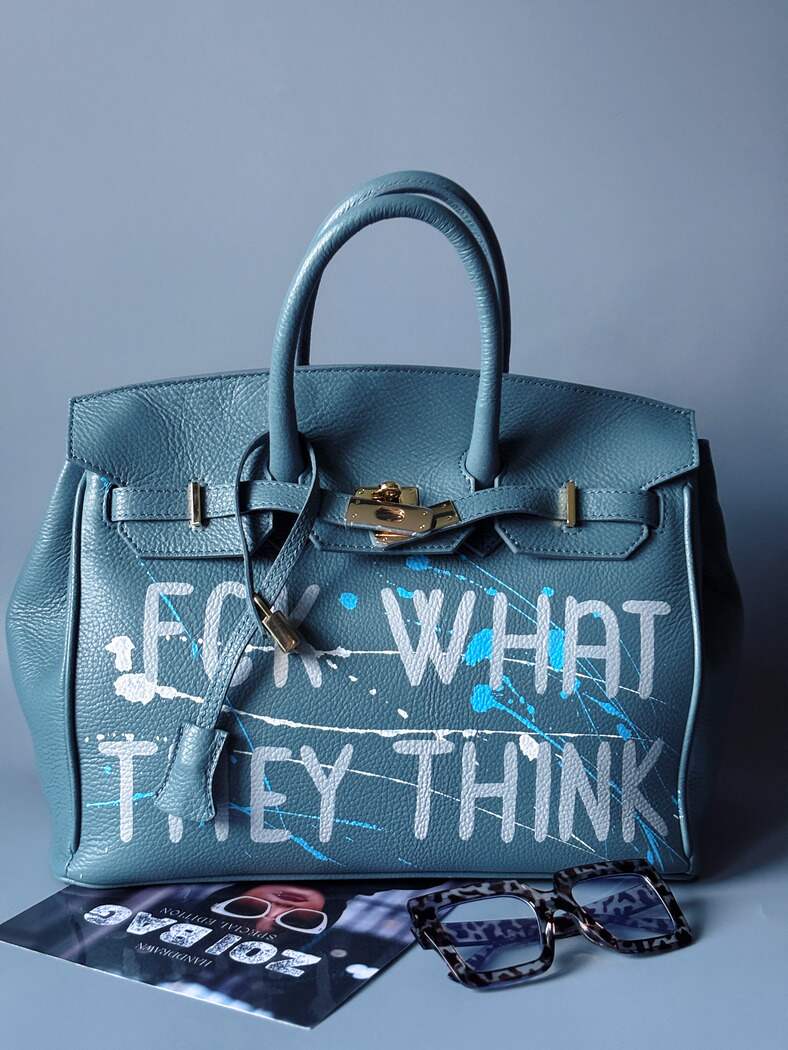 Velká kožená kabelka Zoi Bag v barevné kombinaci modrá a šedá s ručně psaným nápisem "FCK what they think" zapnutá