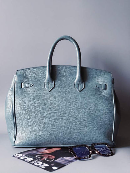 Modrá/šedá kožená kabelka Zoi Bag s ručně psaným nápisem "Can't be tamed" a barevnými cákanci. Zezadu