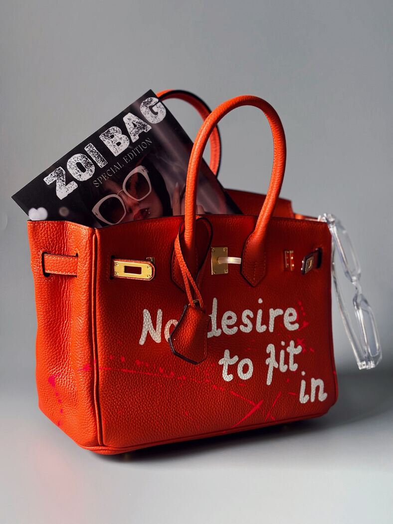 Kožená designová kabelka Zoi Bag v oranžové barvě s nápisem "No desire to fit in" z boku
