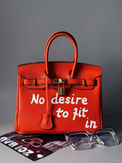 Oranžová designová kožená kabelka Zoi Bag s nápisem "No desire to fit in"
