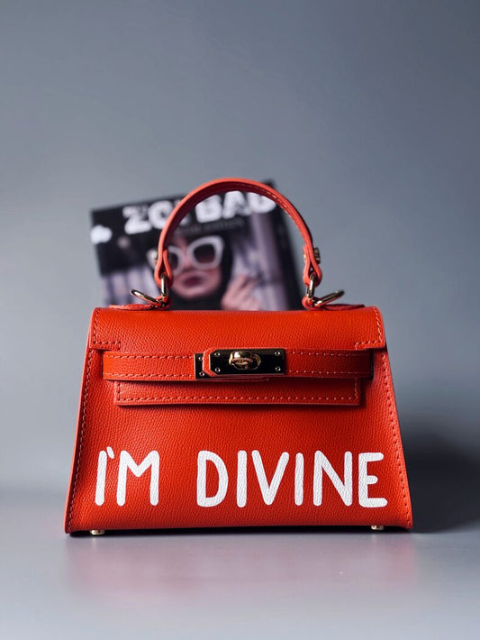 Designová luxusní oranžová kabelka s ručně psaným nápisem, elegantním otočným zámkem a odnímatelným crossbody popruhem.