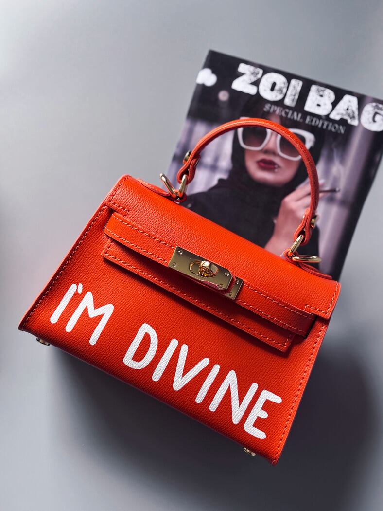 Designová luxusní oranžová kabelka s ručně psaným nápisem, elegantním otočným zámkem a odnímatelným crossbody popruhem.