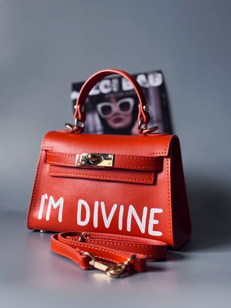Designová luxusní oranžová kabelka s ručně psaným nápisem, elegantním otočným zámkem a odnímatelným crossbody popruhem.
