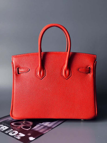 Oranžová kožená kabelka Zoi Bag s ručně psaným nápisem "WTF" a modrými cákanci barvou. Zapínání pomocí zlatého zámku s klíčkem. Zezadu.