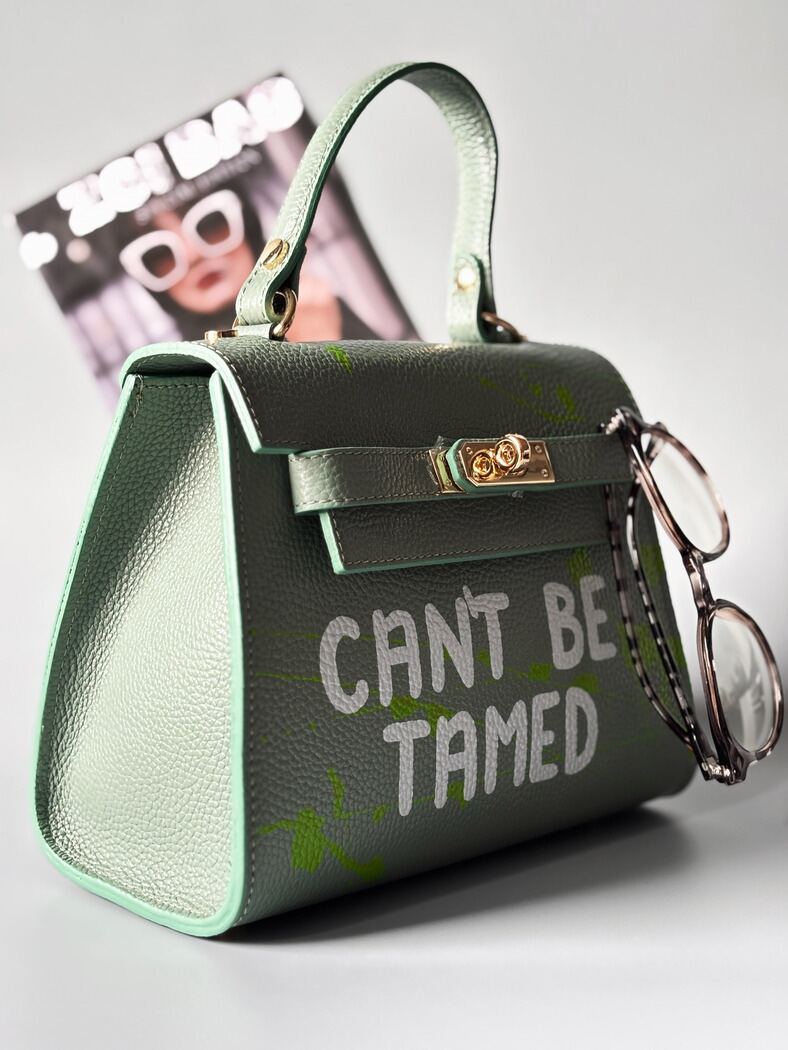 Designová pistáciová kožená kabelka Zoi Bag s ručně psaným nápisem a s cákanci barvou. Zapínání pomocí otočného zlatého zámku.