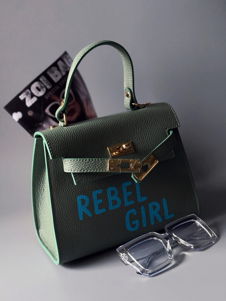 Pistáciová kožená kabelka Zoi Bag s modrým nápisem "Rebel Girl" z  boku