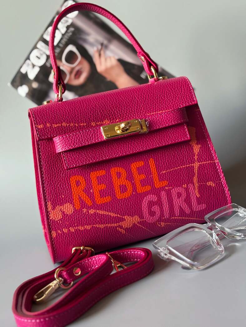 Designová růžová kožená kabelka Zoi Bag s ručně psaným nápisem "Rebel Girl" a cákanci barvou.
