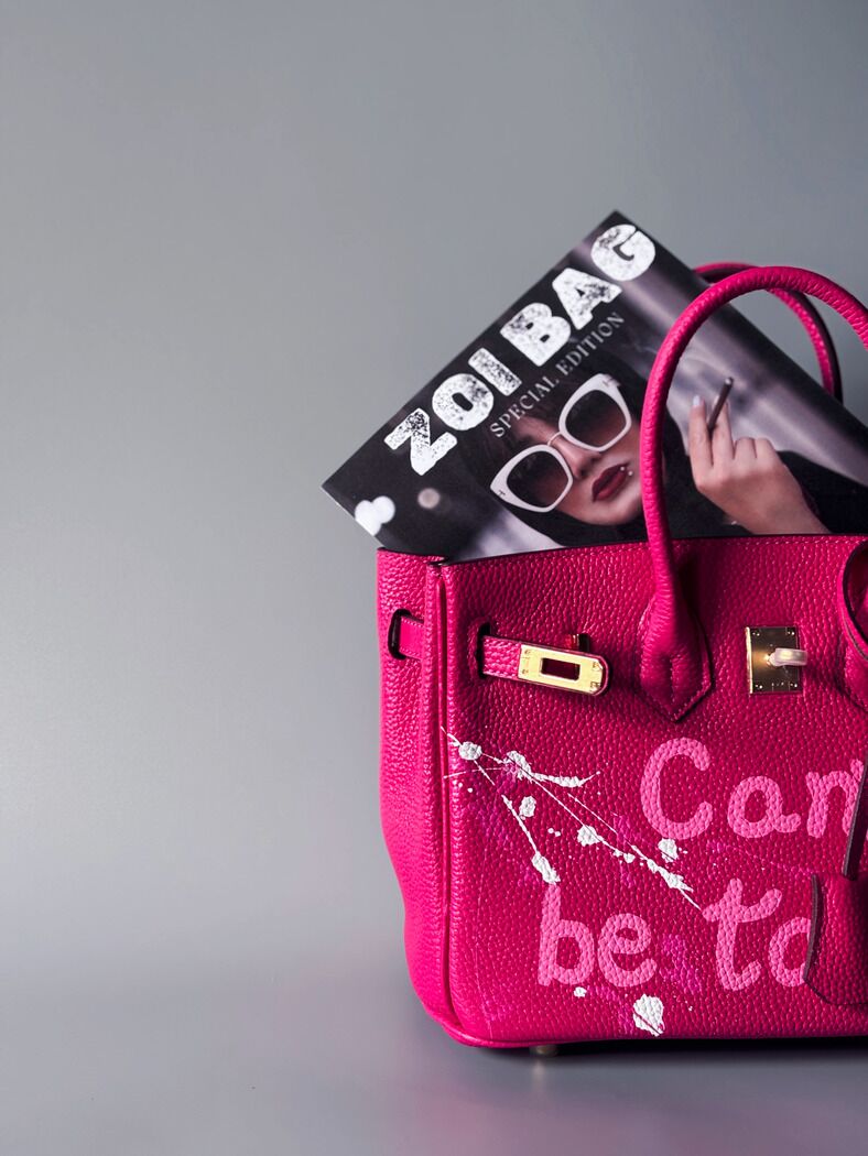 Designová růžová kožená kabelka Zoi Bag s ručně psaným nápisem a s cákanci barvou. Ikonické zapínání pomocí zámku s klíčkem. Detail.