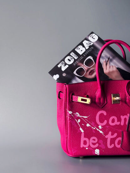 Designová růžová kožená kabelka Zoi Bag s ručně psaným nápisem a s cákanci barvou. Ikonické zapínání pomocí zámku s klíčkem. Detail.