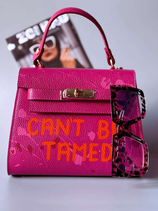 Designová růžová kožená kabelka Zoi Bag s ručně psaným nápisem a s cákanci barvou. Zapínání pomocí otočného zlatého zámku.