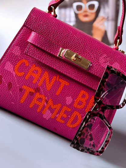 Designová růžová kožená kabelka Zoi Bag s ručně psaným nápisem a s cákanci barvou. Zapínání pomocí otočného zlatého zámku.