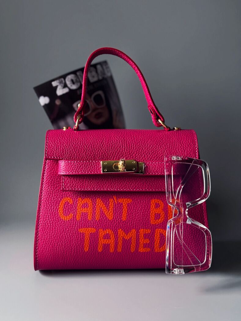 Růžová kožená kabelka Zoi Bag s oranžovým nápisem "Can't be tamed"