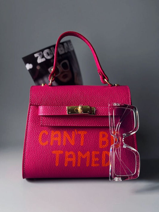 Růžová kožená kabelka Zoi Bag s oranžovým nápisem "Can't be tamed"