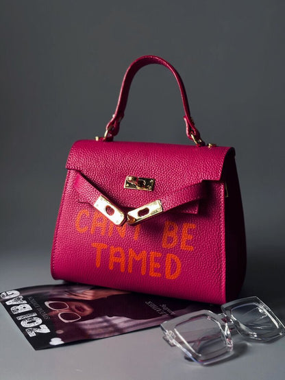 Růžová kožená kabelka Zoi Bag s odvážným nápisem "Can't be tamed"