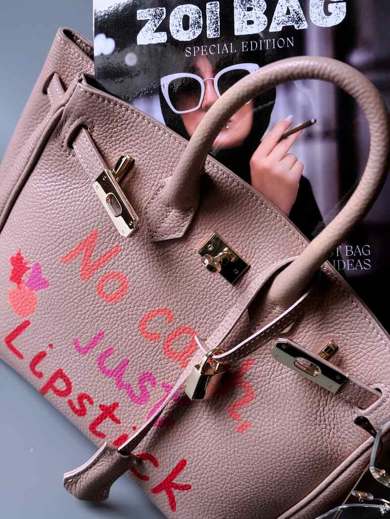 Růžová designová kožená kabelka Zoi Bag s ručně psaným nápisem a cákanci barvou. 