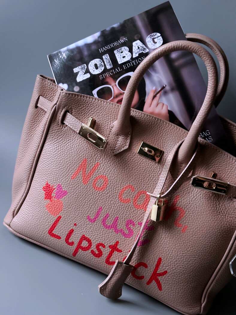 Růžová designová kožená kabelka Zoi Bag s ručně psaným nápisem a cákanci barvou. 