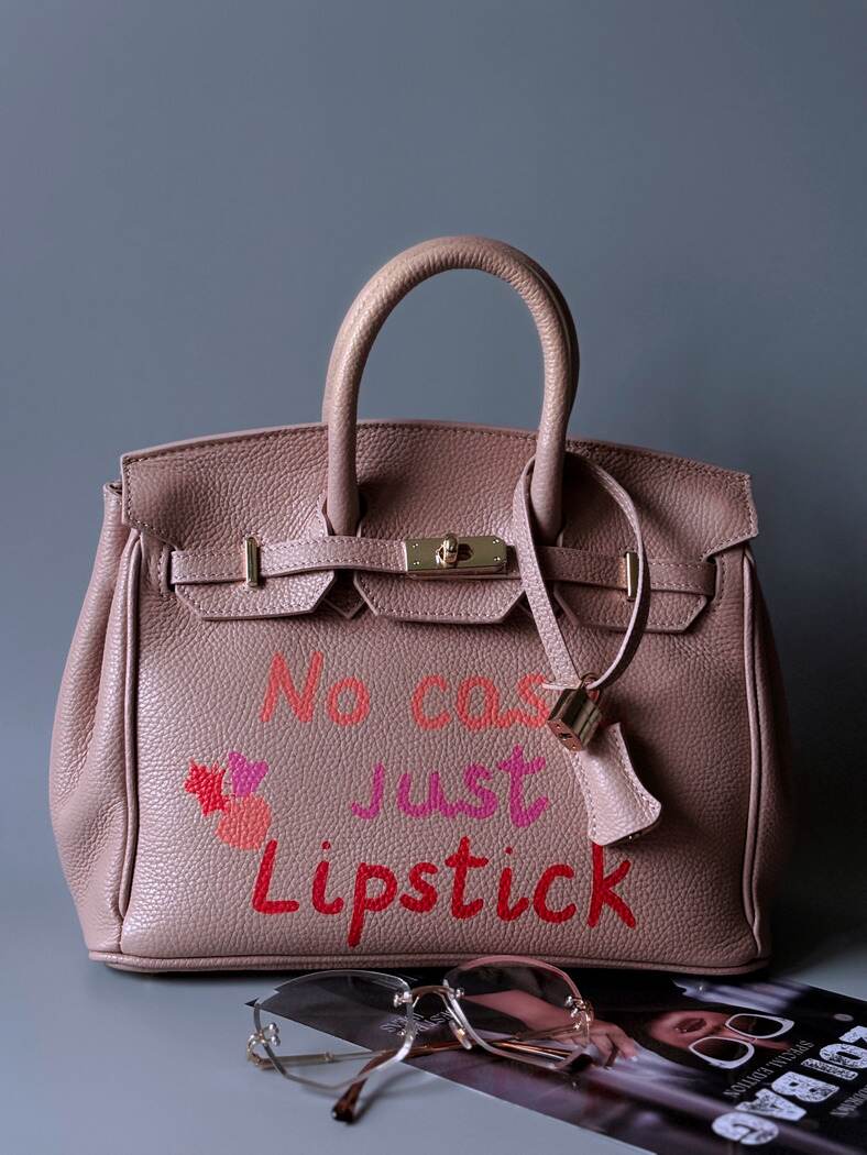 Růžová designová kožená kabelka Zoi Bag s ručně psaným nápisem a cákanci barvou. Zapnutá.