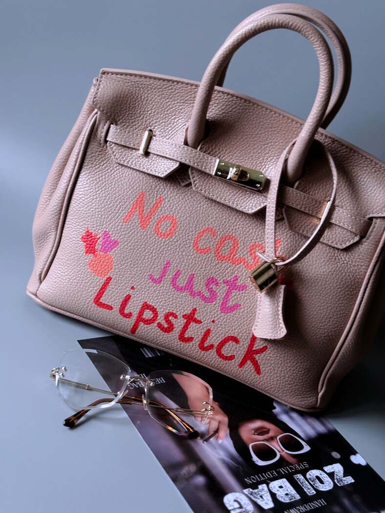 Růžová designová kožená kabelka Zoi Bag s ručně psaným nápisem a cákanci barvou. Zapnutá.