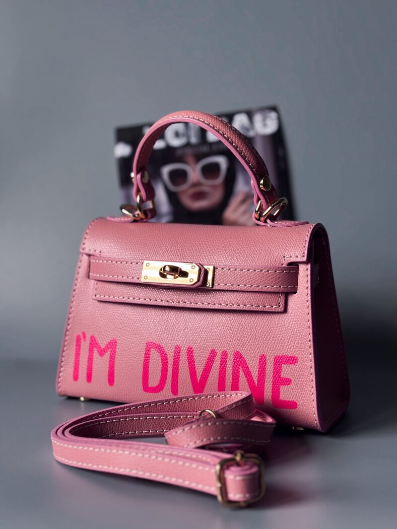 Designová luxusní růžová kabelka s ručně psaným nápisem, elegantním otočným zámkem a odnímatelným crossbody popruhem.