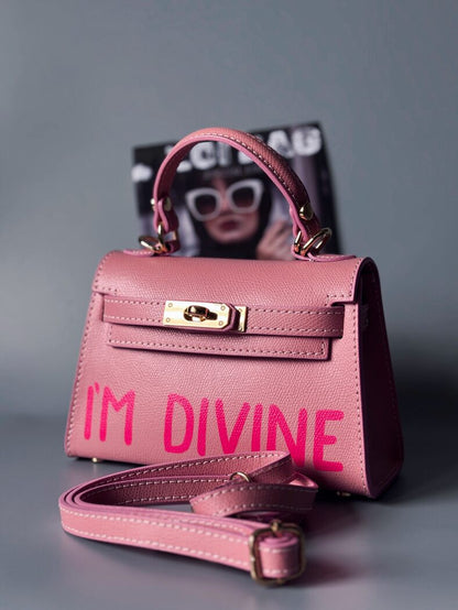 Designová luxusní růžová kabelka s ručně psaným nápisem, elegantním otočným zámkem a odnímatelným crossbody popruhem.