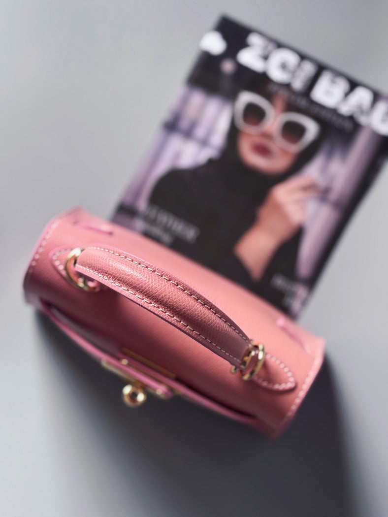 Designová luxusní růžová kabelka s ručně psaným nápisem, elegantním otočným zámkem a odnímatelným crossbody popruhem.