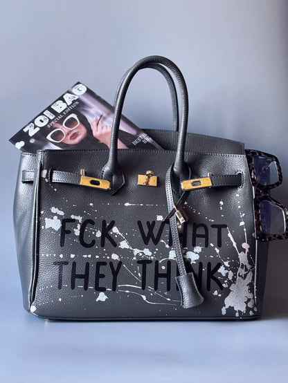 Designová luxusní šedá kožená kabelka Zoi Bag s ručně psaným nápisem a s cákanci barvou. Zapínání pomocí klíčku a zámku.