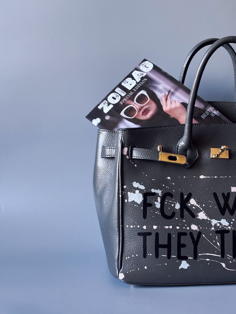 Designová luxusní šedá kožená kabelka Zoi Bag s ručně psaným nápisem a s cákanci barvou. Zapínání pomocí klíčku a zámku. Detail.