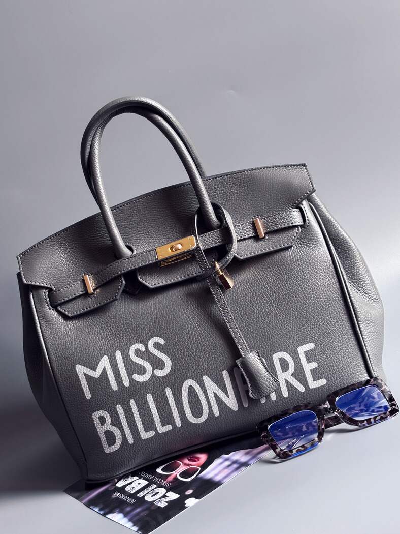 Šedá kožená kabelka Zoi Bag vyrobená z kvalitní italské kůže, s ručně psaným nápisem a se zámkem a klíčkem. Pro personalizaci na zakázku. Zapnutá.