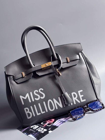 Šedá kožená kabelka Zoi Bag vyrobená z kvalitní italské kůže, s ručně psaným nápisem a se zámkem a klíčkem. Pro personalizaci na zakázku. Zapnutá.