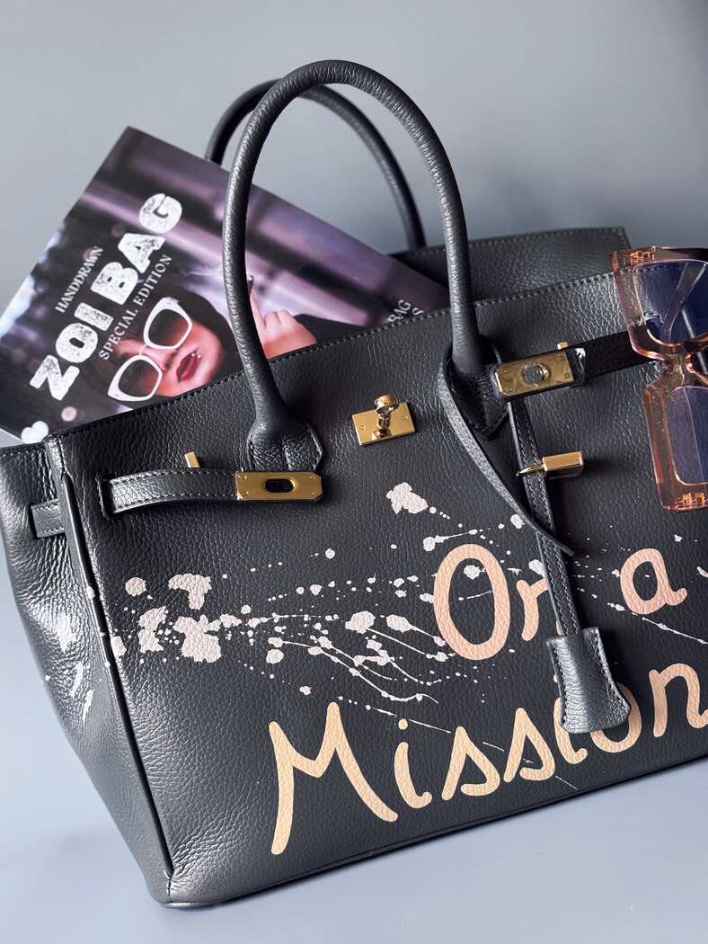 Designová luxusní kožená kabelka s ručně psaným nápisem a s cákanci barvou. Ikonické zapínání pomocí zámku s klíčkem.
