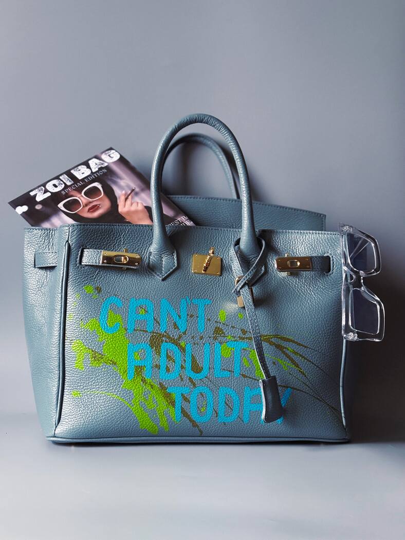 Šedá/modrá velká kožená kabelka Zoi Bag s ručně psaným nápisem "Can't adult today" a barevnými cákanci. Zlatý zámek s klíčkem.