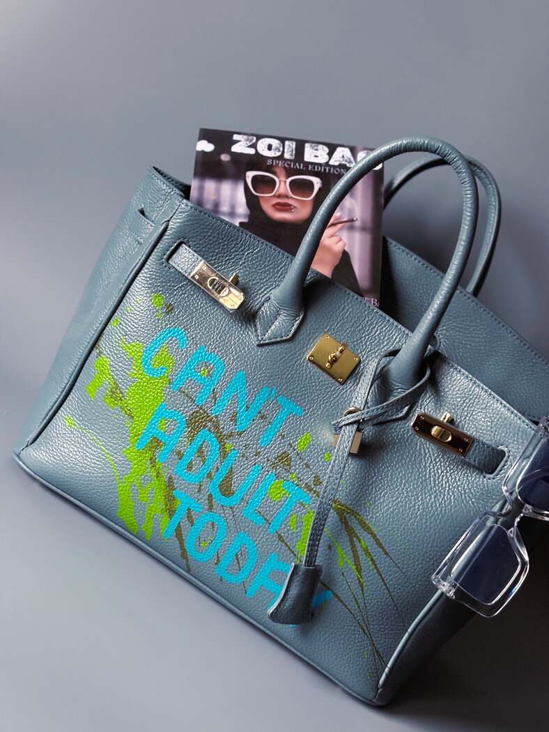 Šedá/modrá velká kožená kabelka Zoi Bag s ručně psaným nápisem "Can't adult today" a barevnými cákanci. Zlatý zámek s klíčkem.