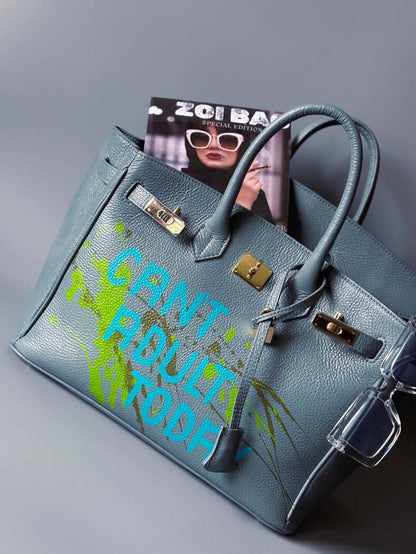 Šedá/modrá velká kožená kabelka Zoi Bag s ručně psaným nápisem "Can't adult today" a barevnými cákanci. Zlatý zámek s klíčkem.