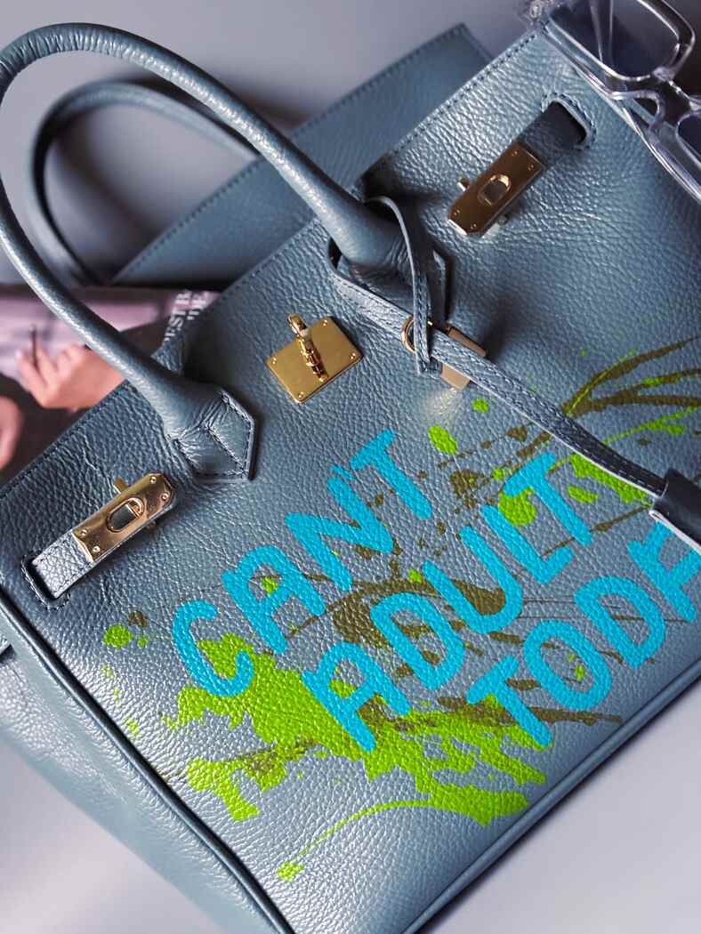 Šedá/modrá velká kožená kabelka Zoi Bag s ručně psaným nápisem "Can't adult today" a barevnými cákanci. Zlatý zámek s klíčkem.