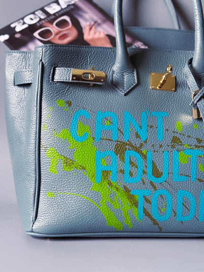 Šedá/modrá velká kožená kabelka Zoi Bag s ručně psaným nápisem "Can't adult today" a barevnými cákanci. Zlatý zámek s klíčkem.