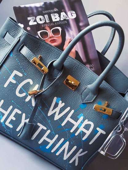 Velká kožená kabelka Zoi Bag v barevných tónech šedé a modré s ručně psaným bílým nápisem "FCK what they think"