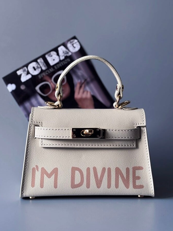 Designová luxusní světle béžová kabelka s ručně psaným nápisem, elegantním otočným zámkem a odnímatelným crossbody popruhem.