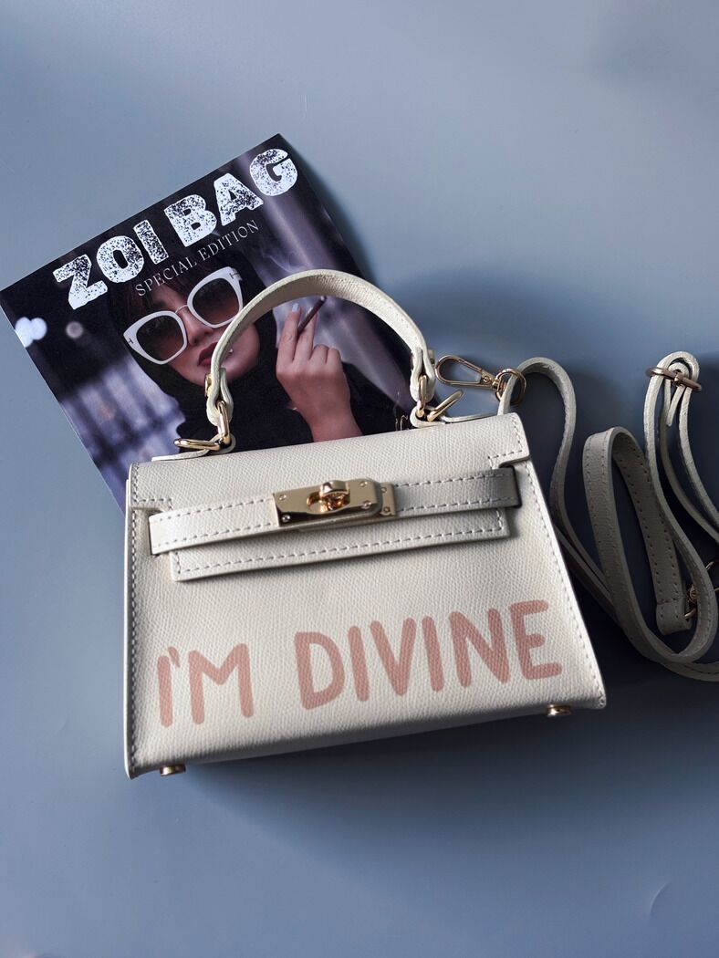 Designová luxusní světle béžová kabelka s ručně psaným nápisem, elegantním otočným zámkem a odnímatelným crossbody popruhem.