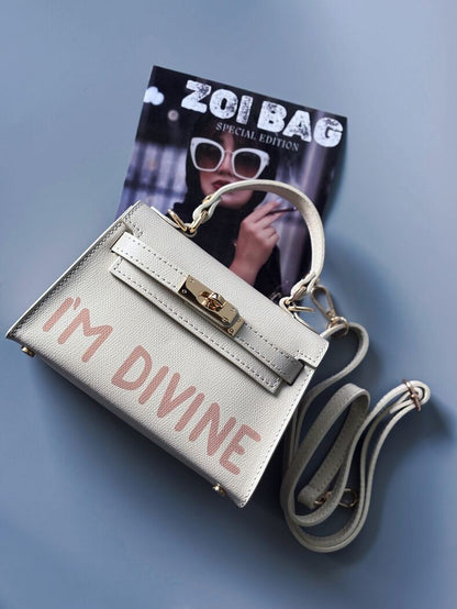 Designová luxusní světle béžová kabelka s ručně psaným nápisem, elegantním otočným zámkem a odnímatelným crossbody popruhem.