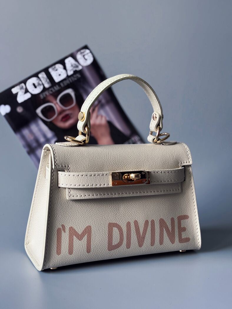 Designová luxusní světle béžová kabelka s ručně psaným nápisem, elegantním otočným zámkem a odnímatelným crossbody popruhem.